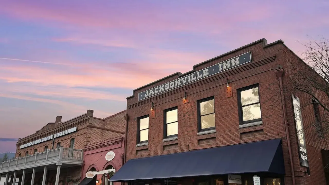 The Jacksonville Inn at dusk, its brick façade lit from the street under a pink sky.