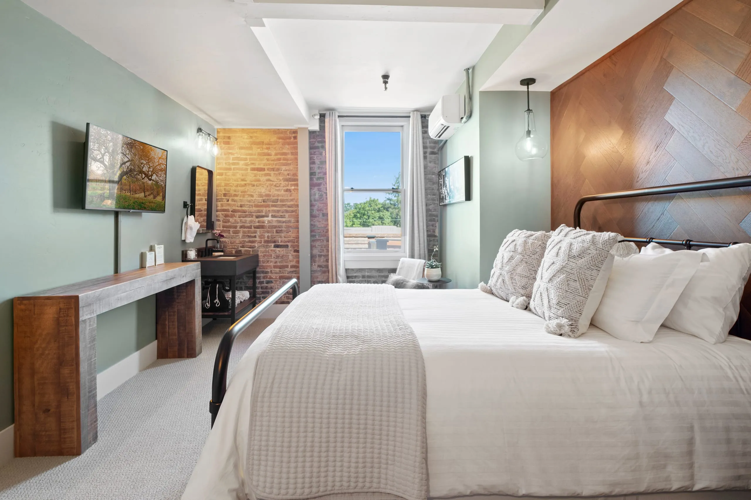 Room #2 at the Jacksonville Inn: Morning light pours through a tall window onto sage walls and warm herringbone oak.