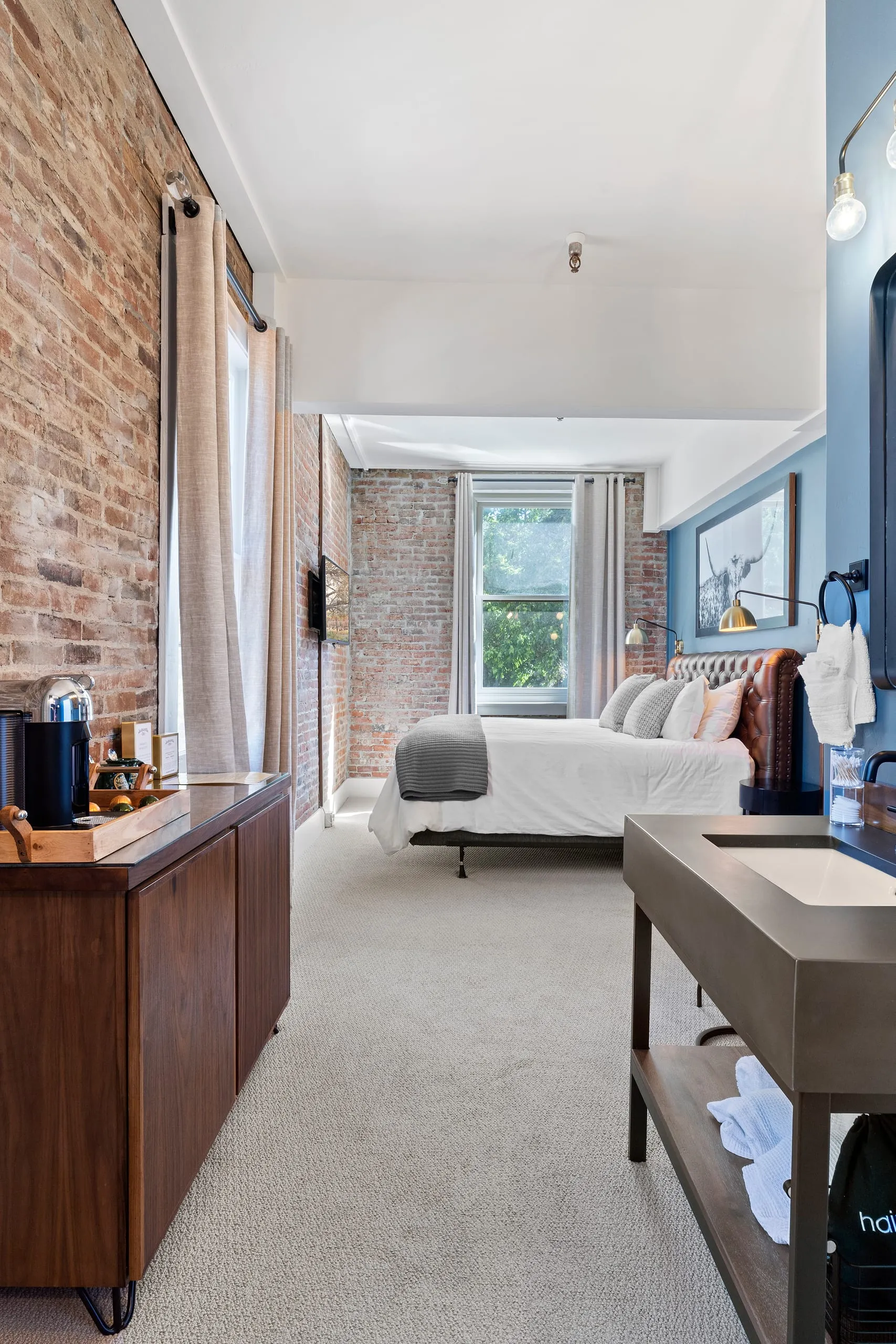 Room #8 at the Jacksonville Inn: Slate blue walls meet original brick and a tufted headboard.